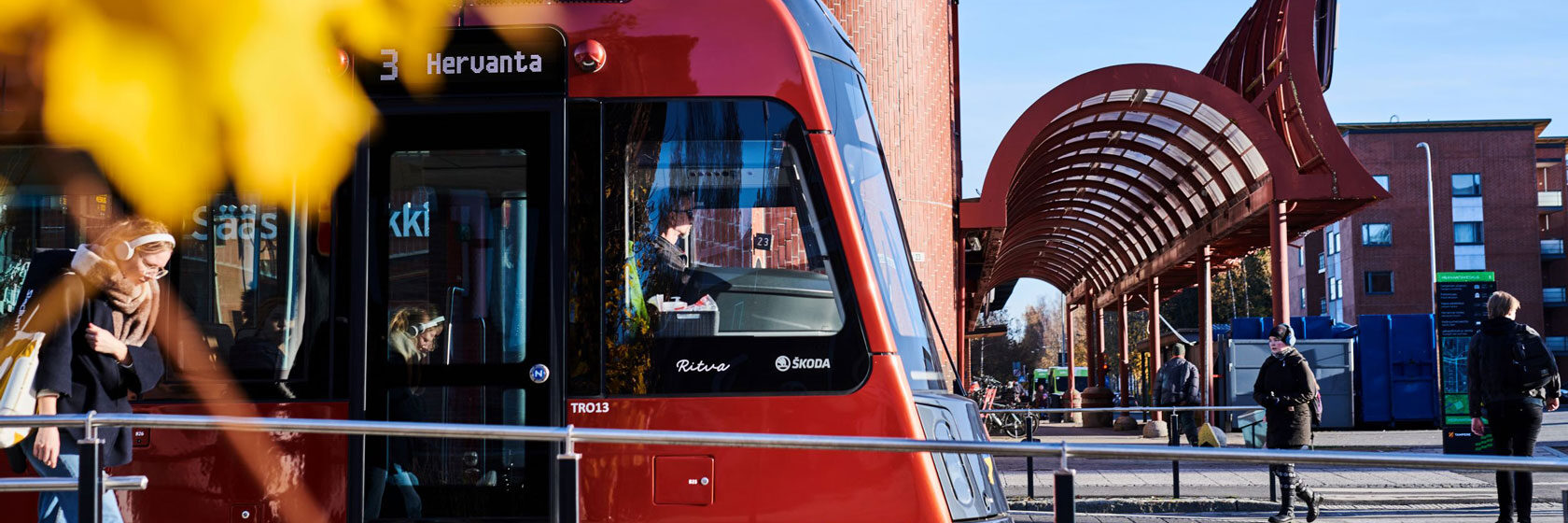 Näkymä Tampereen keskustasta, jossa punainen raitiovaunu ylittää siltaa Näsijärven rannalla.