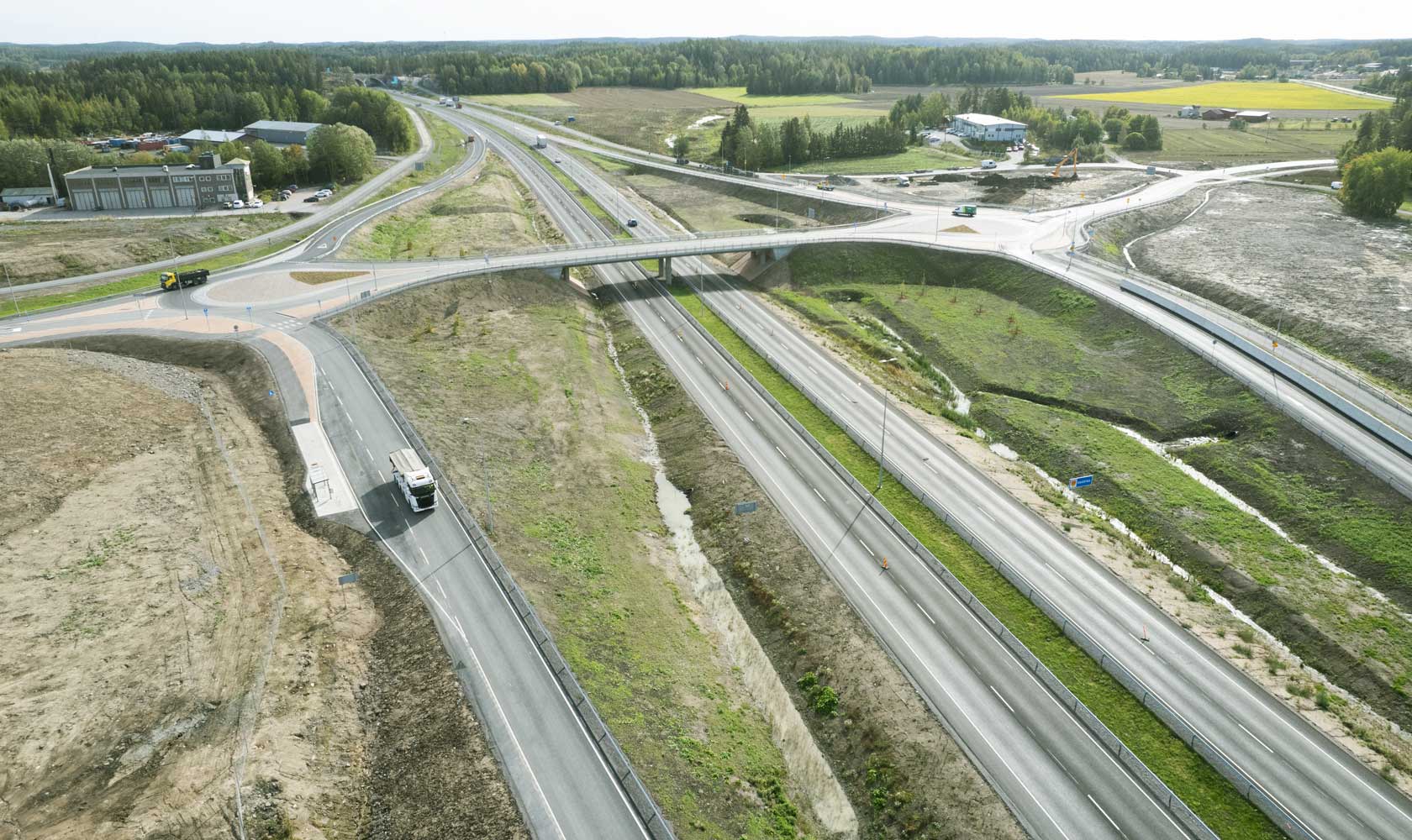 Ilmakuva moottoritie ja risteys lähellä metsää ja peltoja maalaismaisemassa.