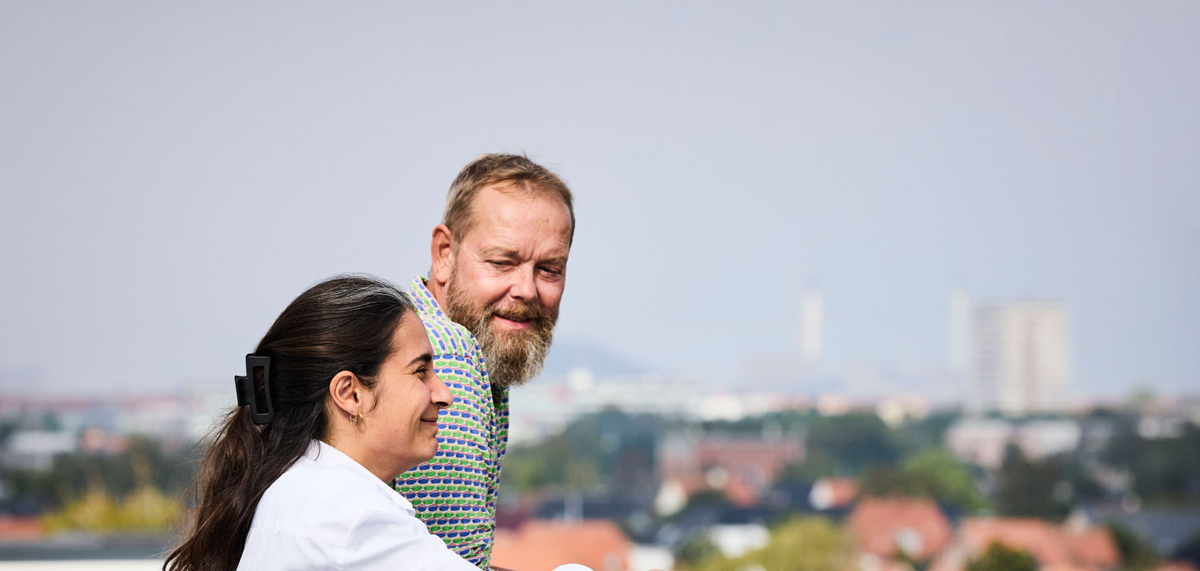 Two persons having a conversation outside. City on the backround