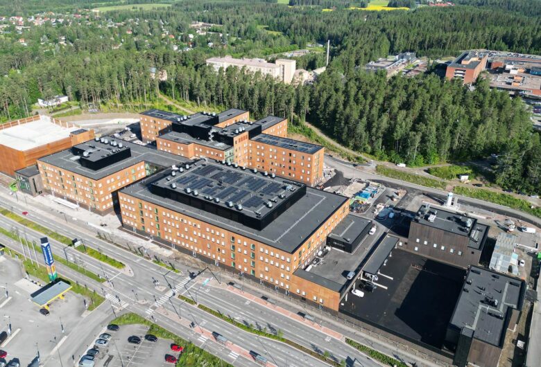 Aerial view of large hospital of Ahvenisto surrounded by forest and residential area in daylight.