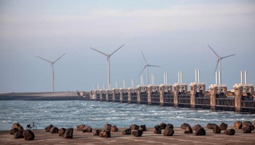 Rannikkonäkymä, jossa taustalla näkyy sarja tuulivoimaloita.