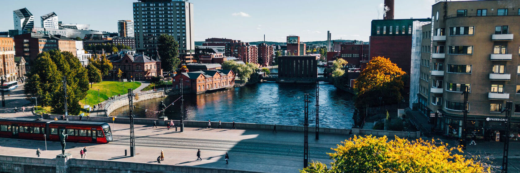 Tampereen keskustaa, jossa näkyy Tammerkoski, silta, raitiovaunu ja rakennuksia.