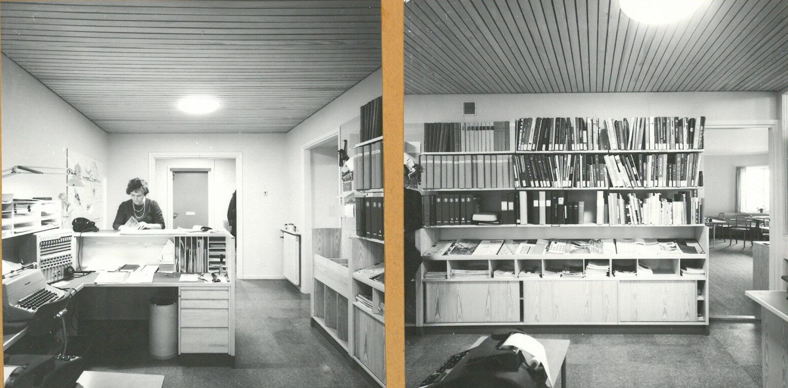 Mustavalkoinen valokuva Swecon toimistosta, jossa vasemmalla puolella näkyy työpöytä kirjoituskoneineen ja hyllyjä täynnä papereita ja kansioita. Oikealla puolella on suuri kirjahylly, kirjoja ja kansioita sekä pöytä, jolla on papereita.