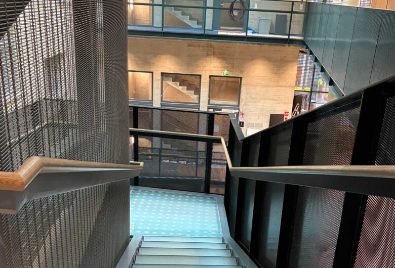 Modern indoor staircase with metal railings, leading to a bright, open office space.