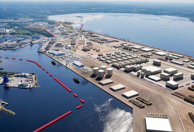 Aerial view of an industrial port with storage tanks, warehouses, and docks near a bay.