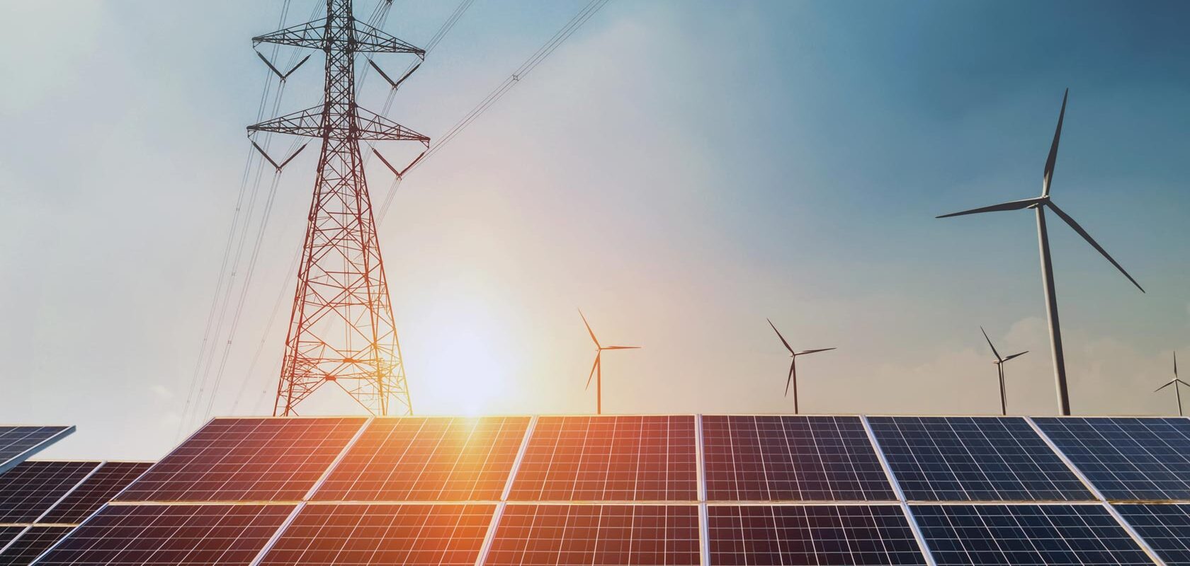 Aurinkopaneelit, tuulivoimalat ja sähkölinjat kirkkaassa auringonpaisteessa