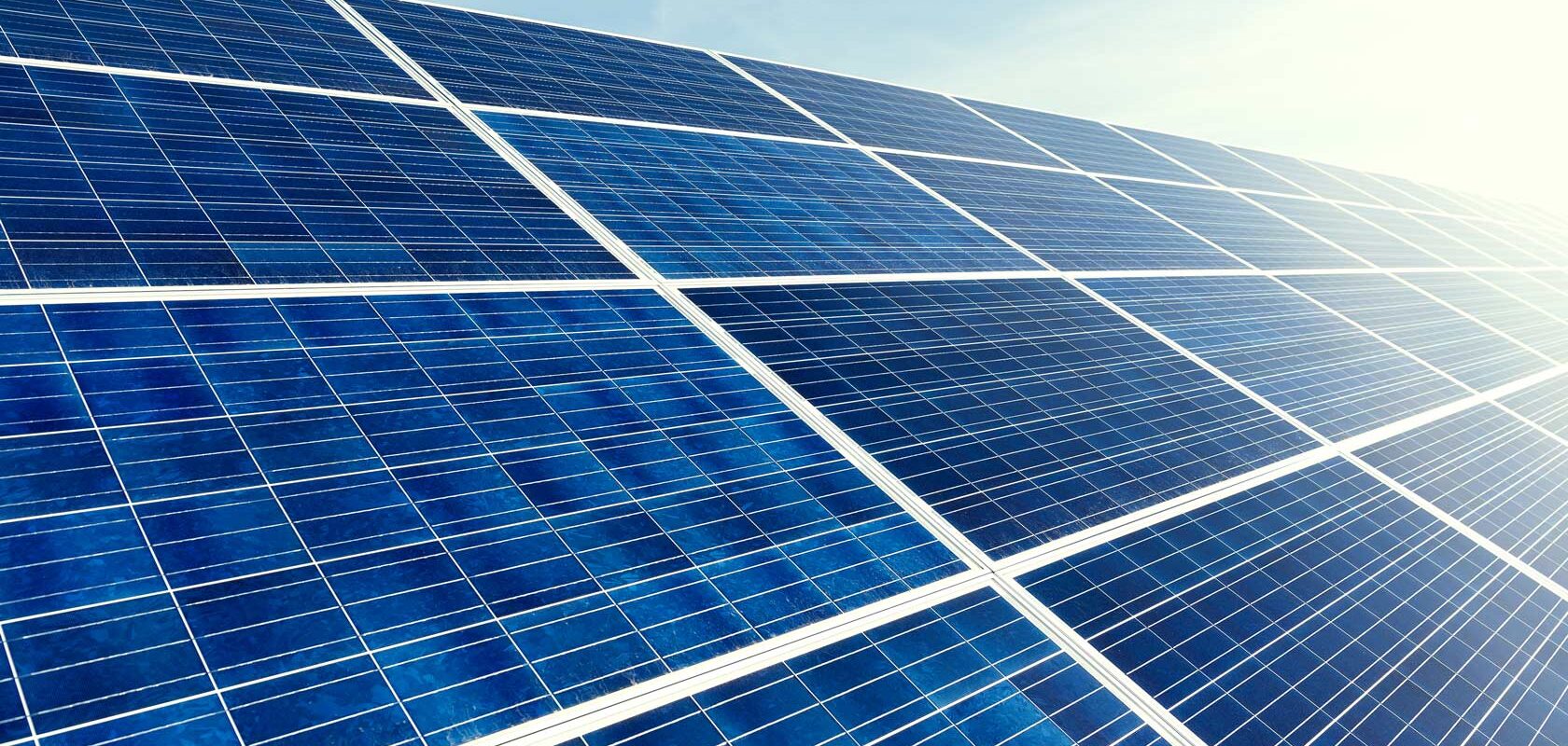 Aurinkopaneelit kirkkaassa auringonpaisteessa sinistä taivasta vasten.