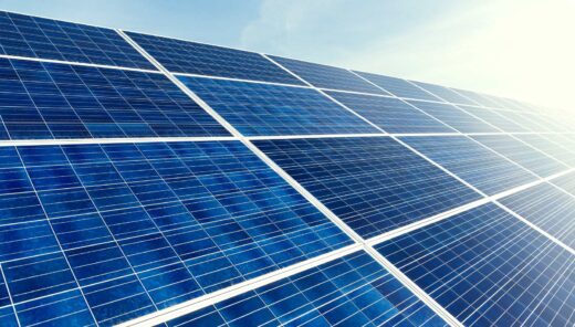 Aurinkopaneelit kirkkaassa auringonpaisteessa sinistä taivasta vasten.