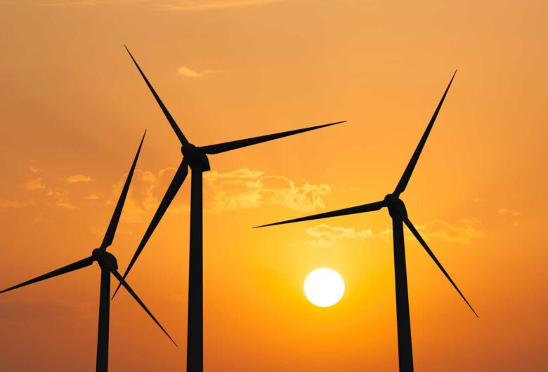 Kolme tuulivoimalaa auringonlaskussa.