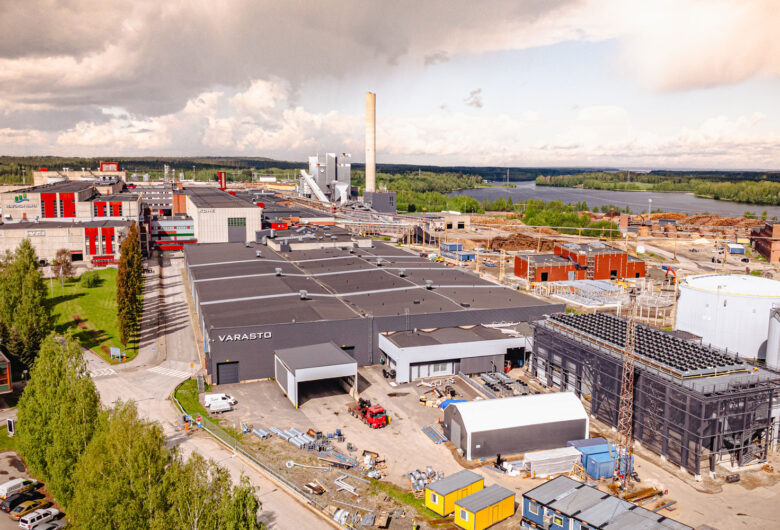 Tehdasalue suomalaisessa kaupungissa, taustalla järvi ja metsä.