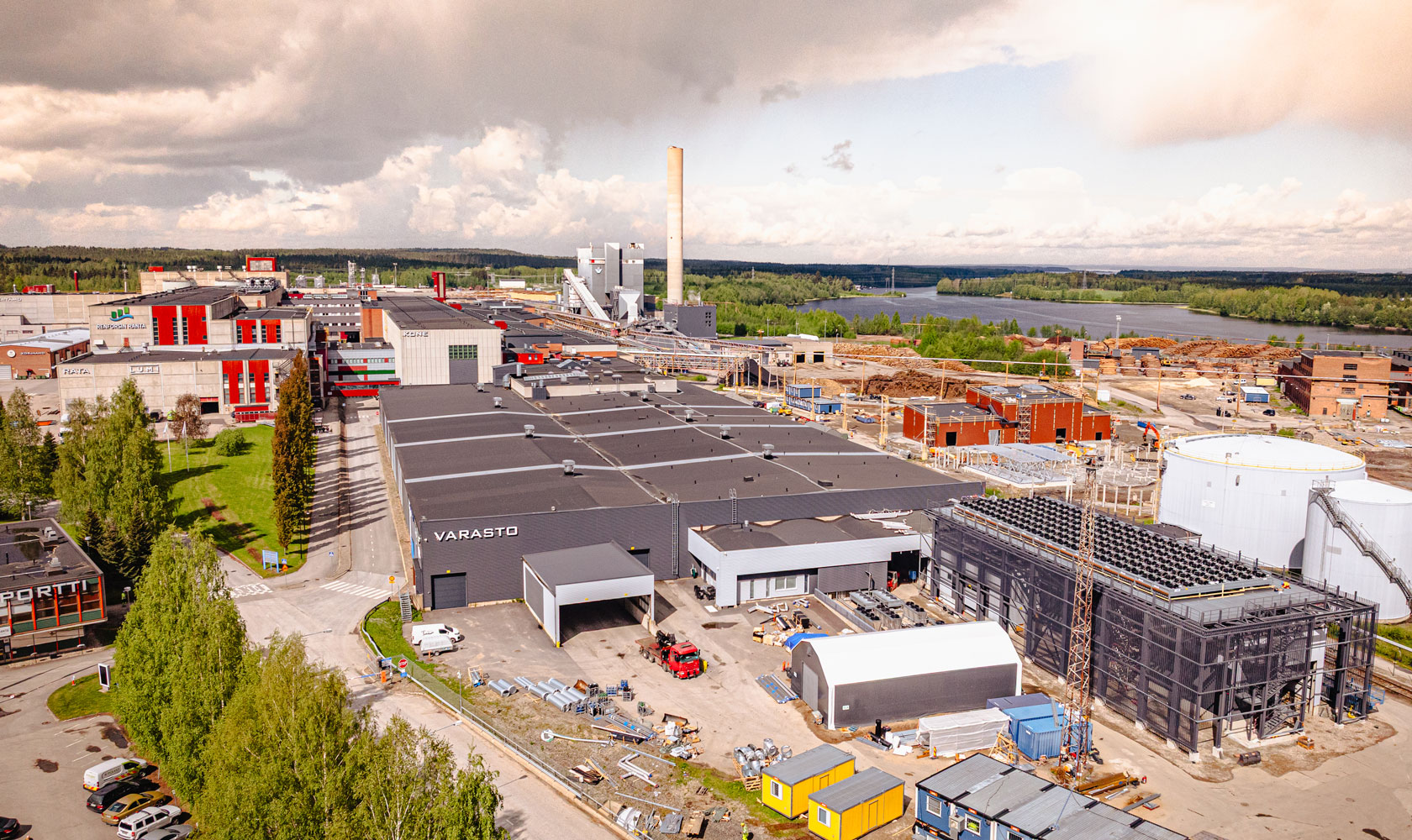 Tehdasalue suomalaisessa kaupungissa, taustalla järvi ja metsä.