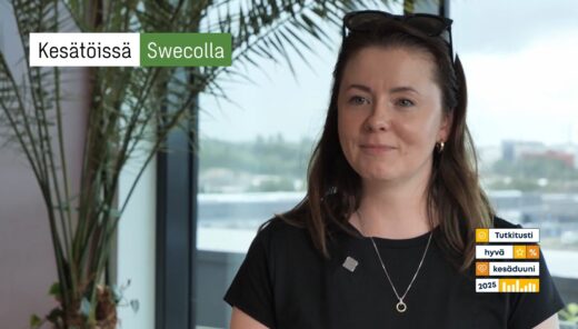 Nainen kesätöissä Swecolla, musta paita ja kaulakoru, taustalla kasveja ja ikkunasta kaupunkinäkymä.