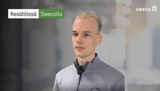 Nuori mies harmaassa paidassa. Taustalla moderni toimisto