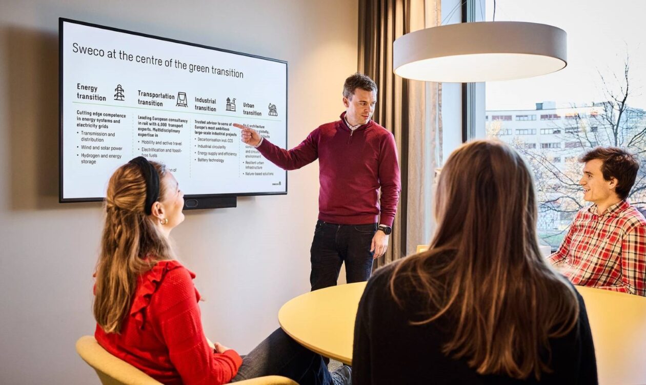 Neljä henkilöä pyöreän pöydän ääressä, yksi esittelee globaaleja megatrendejä