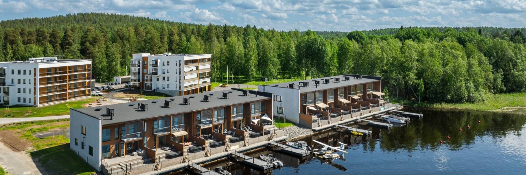 Kaksikerroksinen rivitalo järven äärellä, asunnoissa omat laiturit