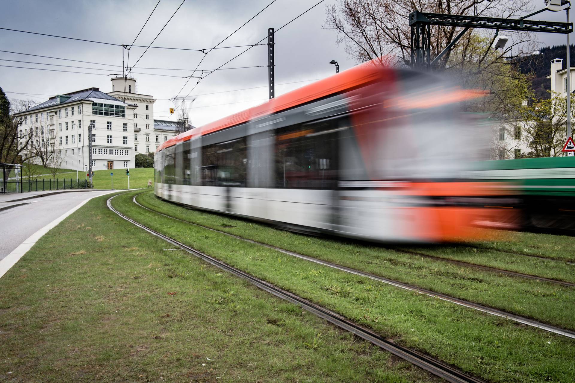 Nopeasti ohi vilahtava raitiovaunu nurmikkoisella radalla.