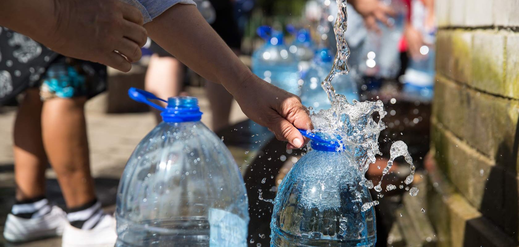 People in a public square filling water canisters.