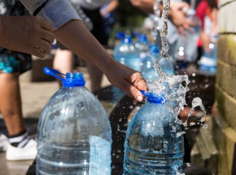 People in a public square filling water canisters.