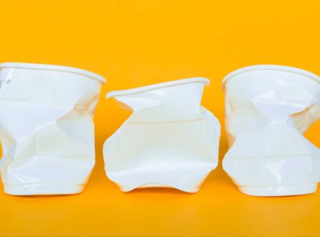 Kolme valkoista muovipurkkia apelsiininkeltaisella taustalla.