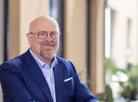 Thomas Hietto kuvattuna toimistolla suuren ikkunan edessä.