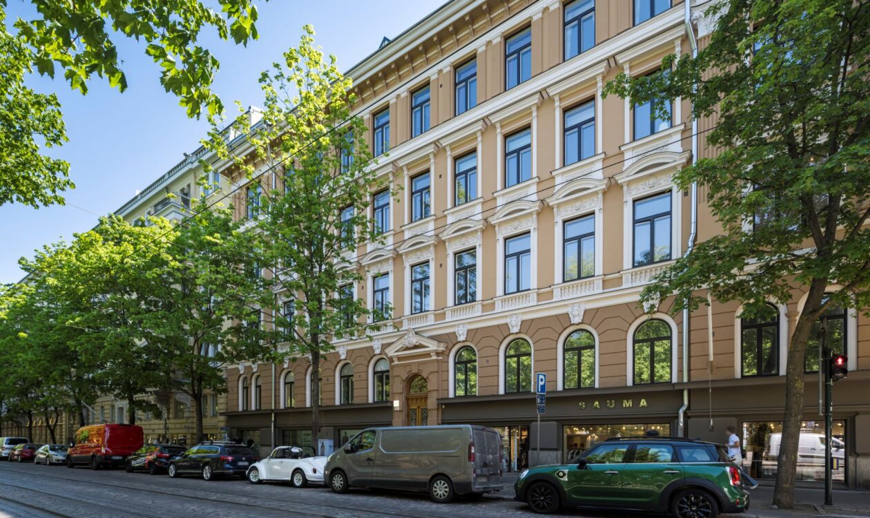 Old, renovated building in Helsinki in the summer time. Cars are parked in front of the building.