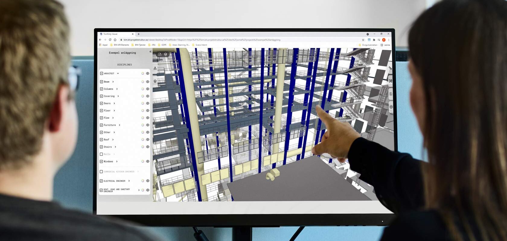 Kaksi suunnittelijaa tarkastelee 3D-rakennusmallia tietokoneen näytöllä
