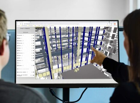 Kaksi suunnittelijaa tarkastelee 3D-rakennusmallia tietokoneen näytöllä