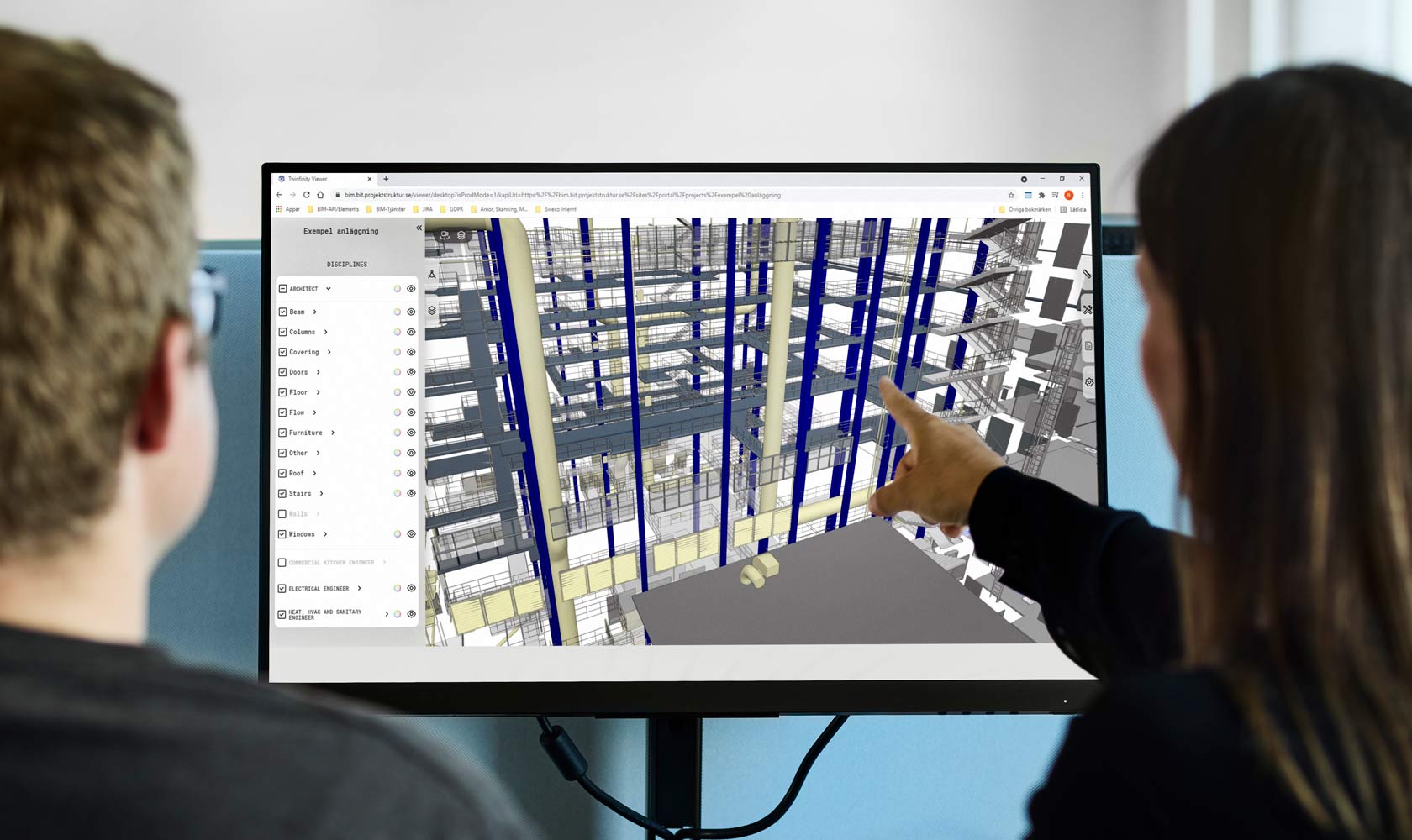 Kaksi suunnittelijaa tarkastelee 3D-rakennusmallia tietokoneen näytöllä