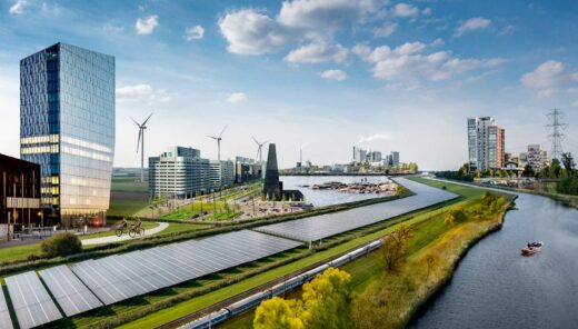 Modern sustainable city with solar panels, wind turbines, river, train and high-rise buildings.