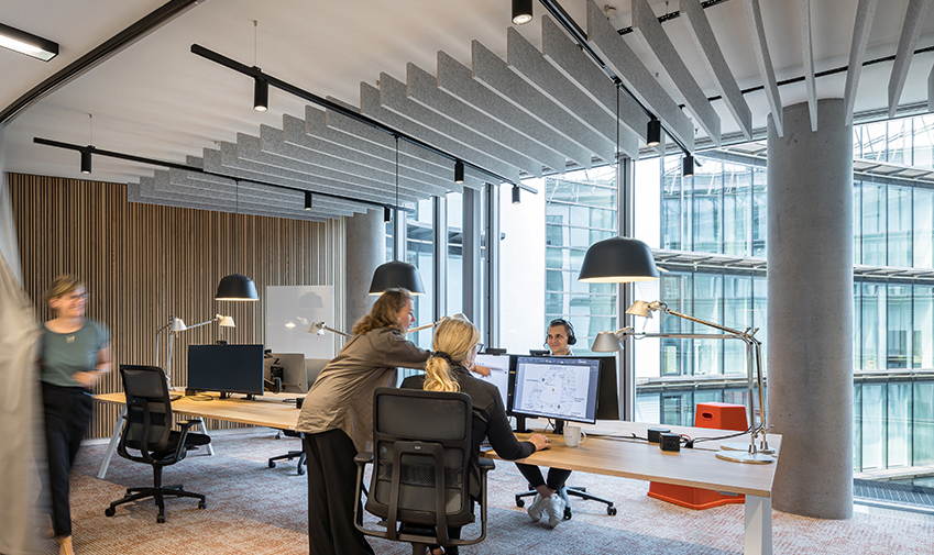 Moderni avotoimisto, jossa työntekijät työskentelevät tietokoneilla suurten ikkunoiden äärellä.