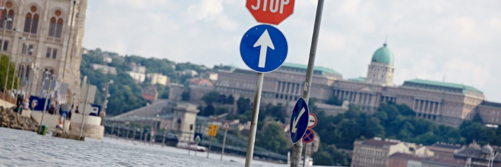 Kadut tulvivat Budapestissä, taustalla näkyy parlamenttitalo, kuvan edustalla liikennemerkki, joka jäänyt tulvaveden alle.