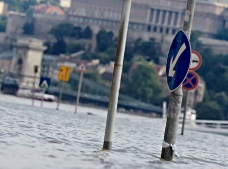 Kadut tulvivat Budapestissä, taustalla näkyy parlamenttitalo, kuvan edustalla liikennemerkki, joka jäänyt tulvaveden alle.