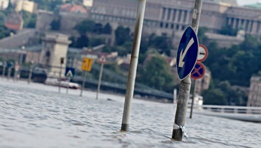Kadut tulvivat Budapestissä, taustalla näkyy parlamenttitalo, kuvan edustalla liikennemerkki, joka jäänyt tulvaveden alle.