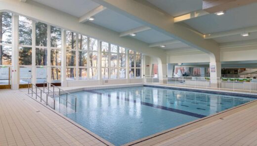 Bright indoor swimming pool with large windows and accessible ramp