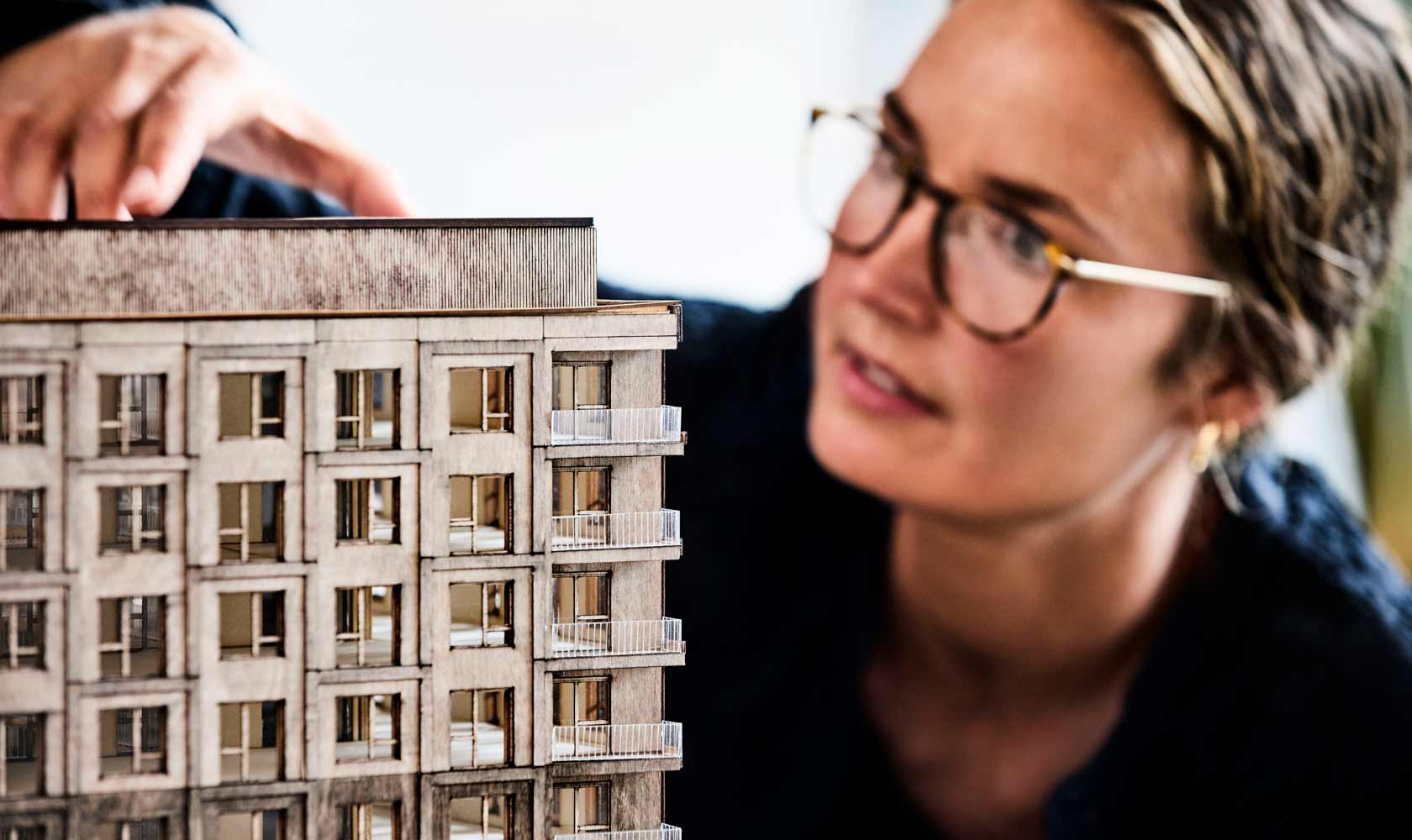 Arkkitehti esittelee kerrostalon pienoismallia pöydällä