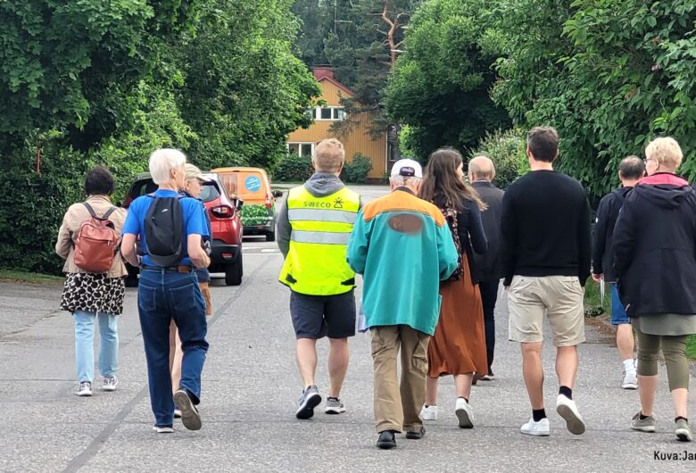 Group walking on a tree-lined residential street during guided neighborhood tour.