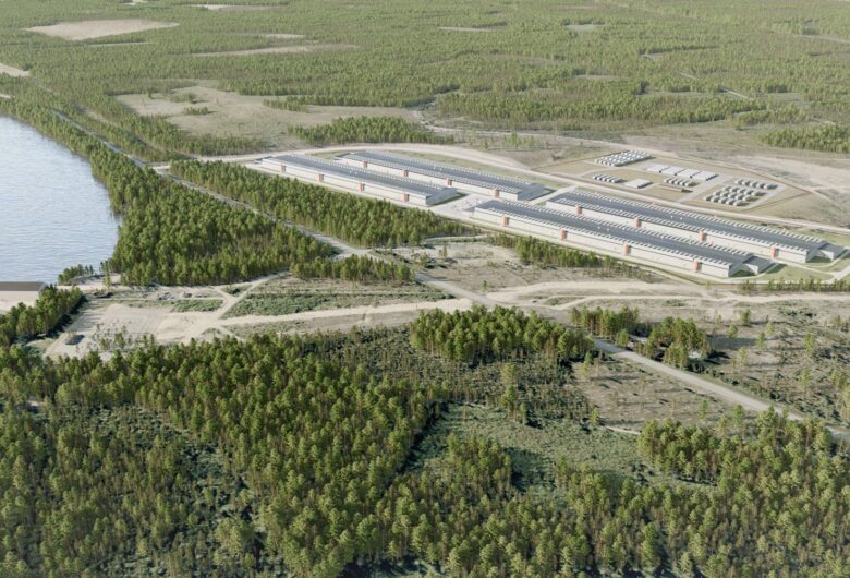 Ilmakuva teollisuuslaitoksesta järven rannalla, ympärillä metsää ja teitä.