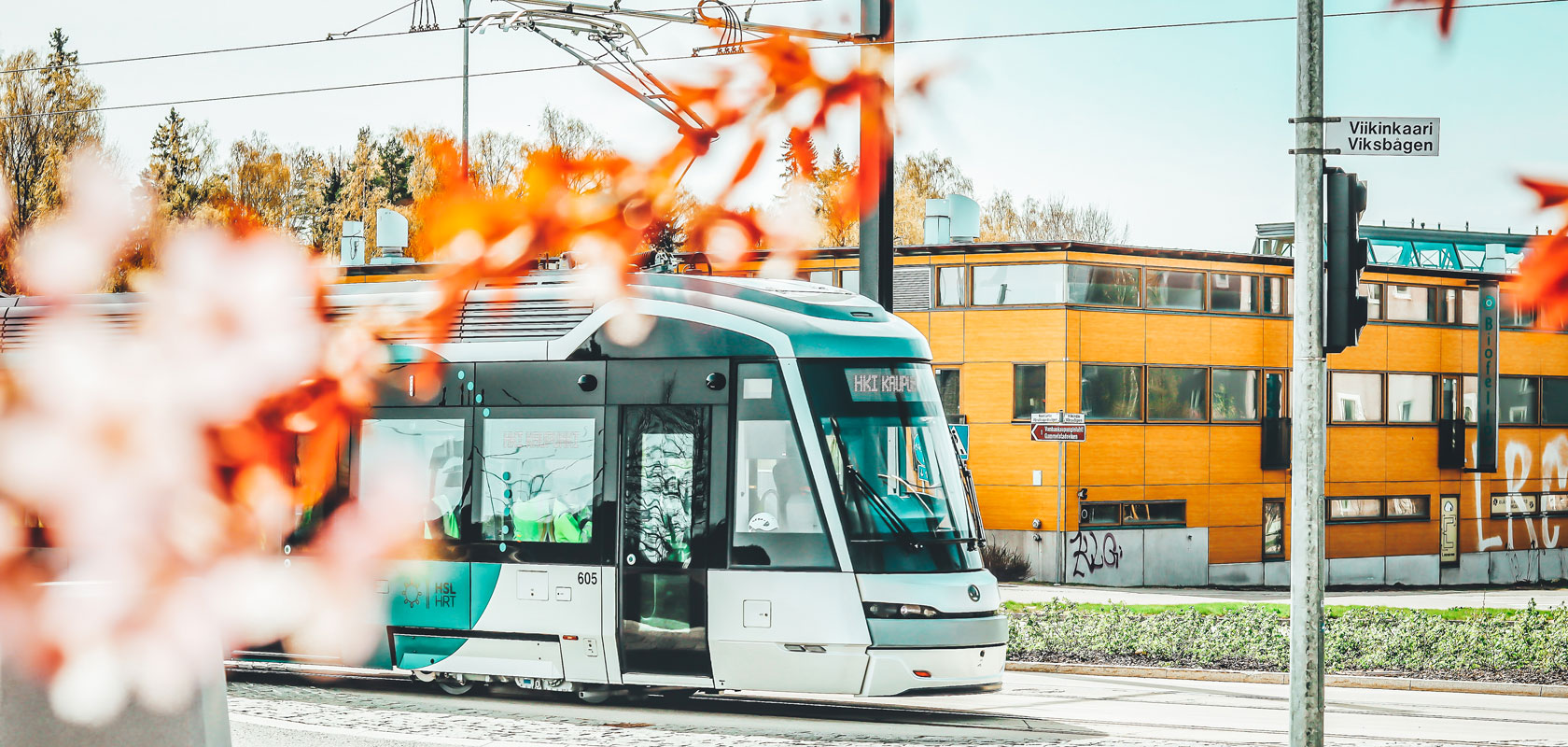 Modern tram on Helsinki street with autumn leaves and Viikinkaari sign