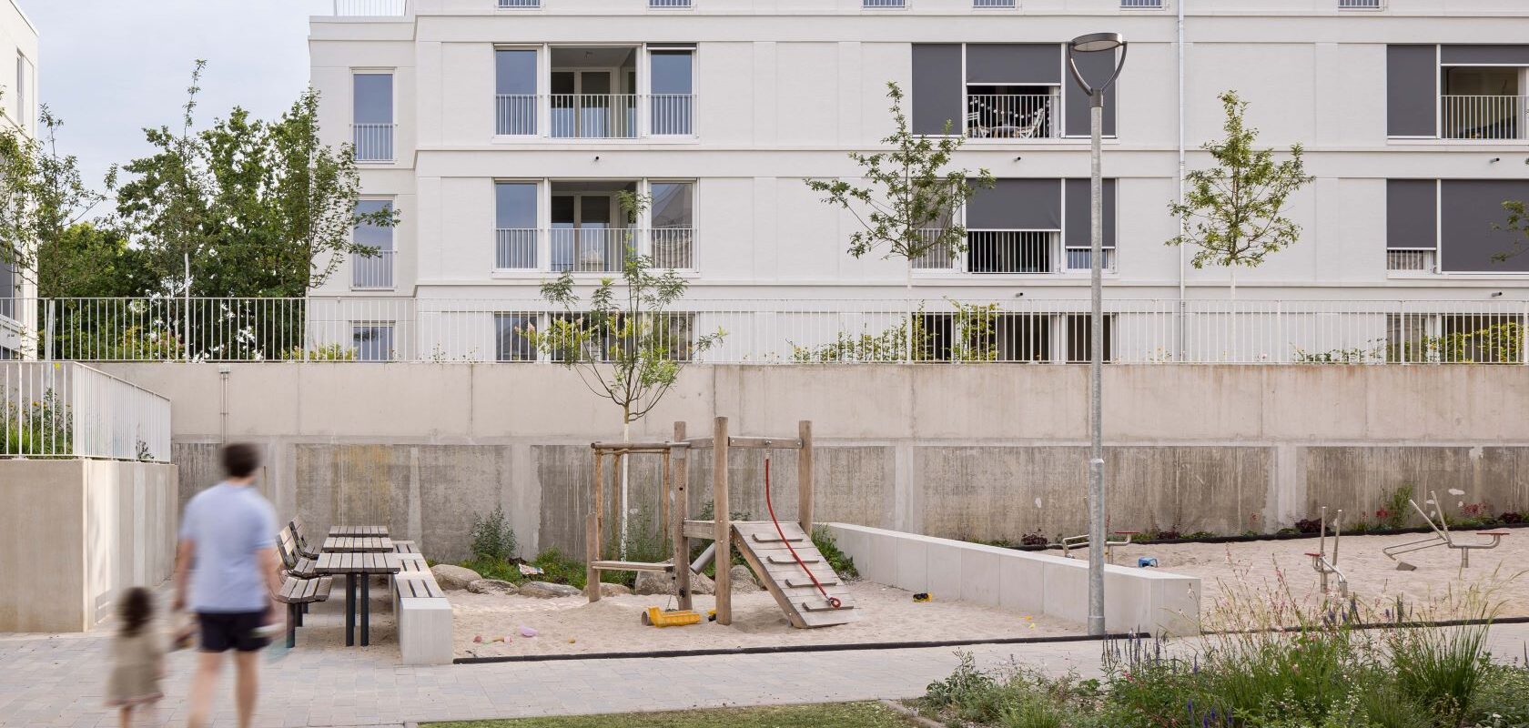 A yeard of a housing company. Parents with a child outside.