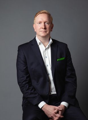Jaakko Sarpon kuva, henkilö tummassa puvussa.