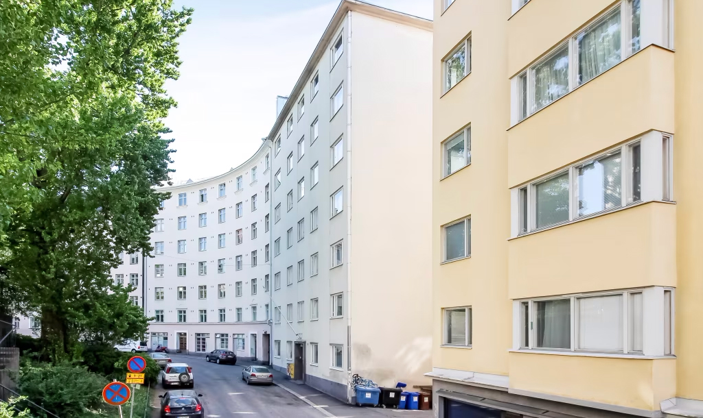 Energia-avustukset. Vaaleiksi rapattuja vanhoja kerrostaloja kaupunkikadun varrella kesäpäivänä.